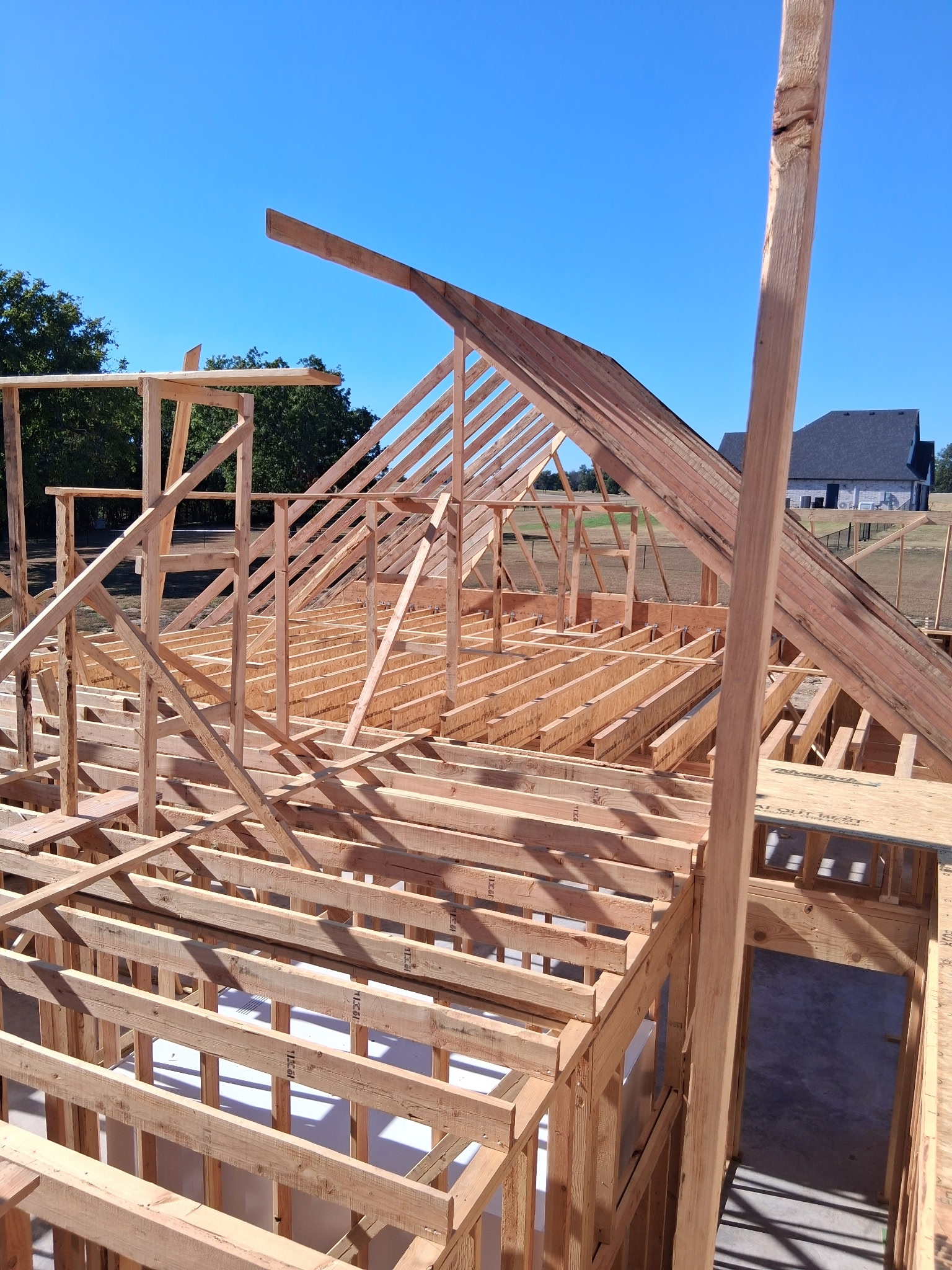 Residential roof framing and floor joists on a new home build under a clear blue sky