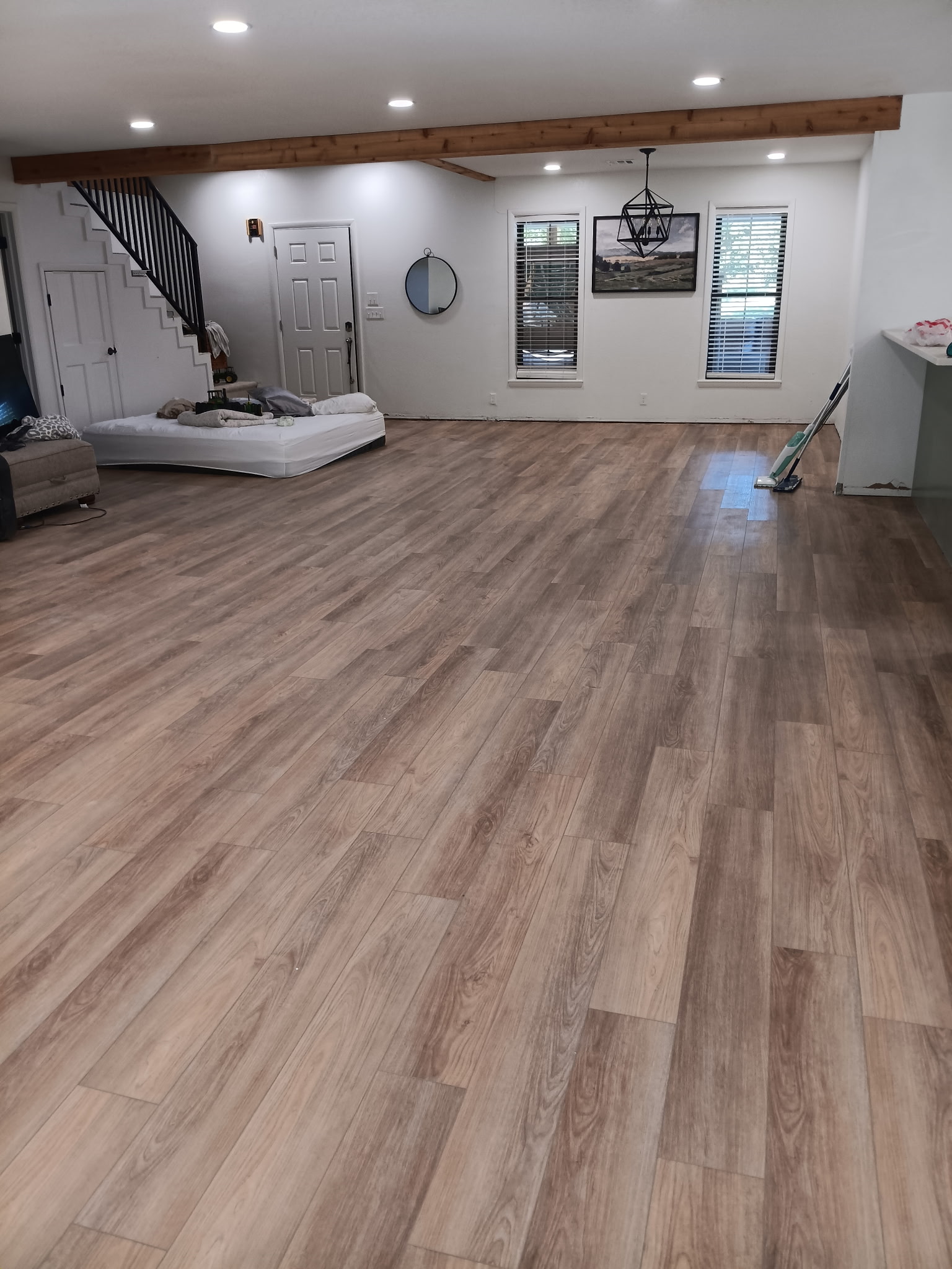 Open living area with new wood-look flooring and a finished ceiling beam