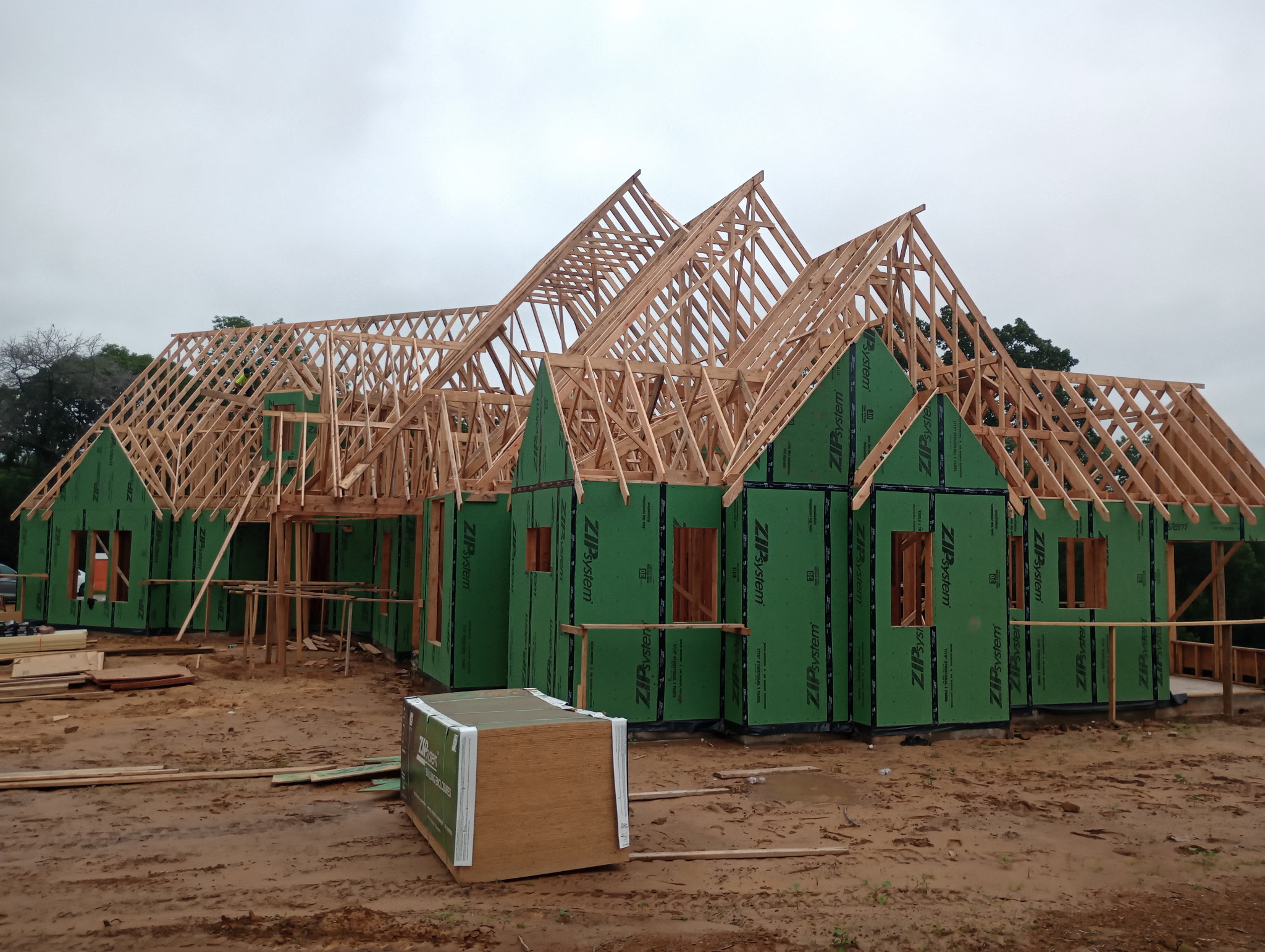 Wide view of a new house framed and sheathed, with multiple roof trusses