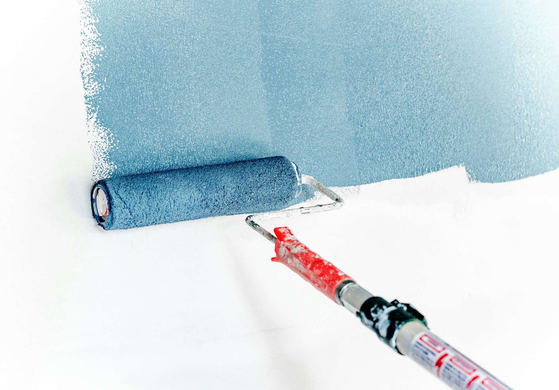 Paint roller laying a fresh coat on an interior wall